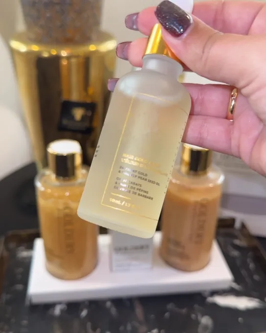 Main tenant un flacon de sérum pour les cheveux devant les produits du centre